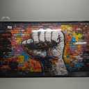 Framed Canvas print featuring a vibrant graffiti-style clenched fist artwork on a multicolored brick wall 60L X 30W
